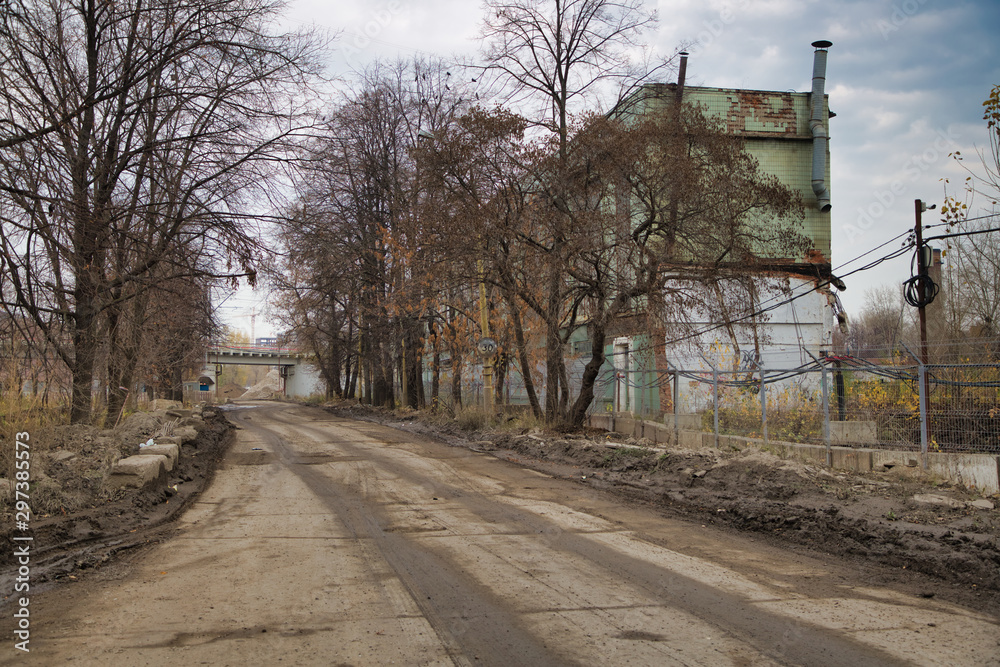 Abandoned industry building and construction, autumn, poor road