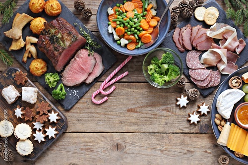 Christmas dinner table with roast beef, appetizers platter and traditional cookies. Christmass celebration, festive family dinner.  Overhead view.