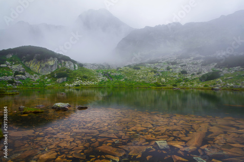 Wet stones on  T  ul Por  ii  lake coast in foggy  autumn morning. The fog spreads over the water.