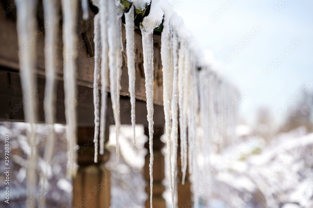 Spring landscape with ice icicles hanging from roof of house. Spring landscape with ice icicles hanging from roof of house.