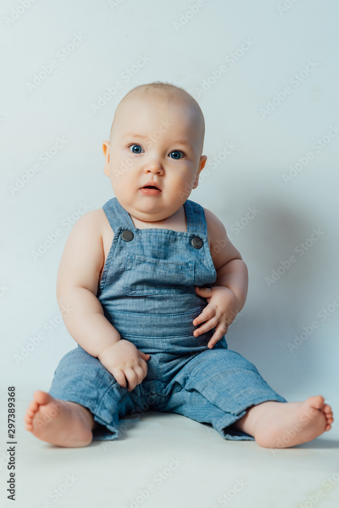 Little surprised boy sits on a white background and looks at the camera Little surprised boy sits on a white background and looks at the camera