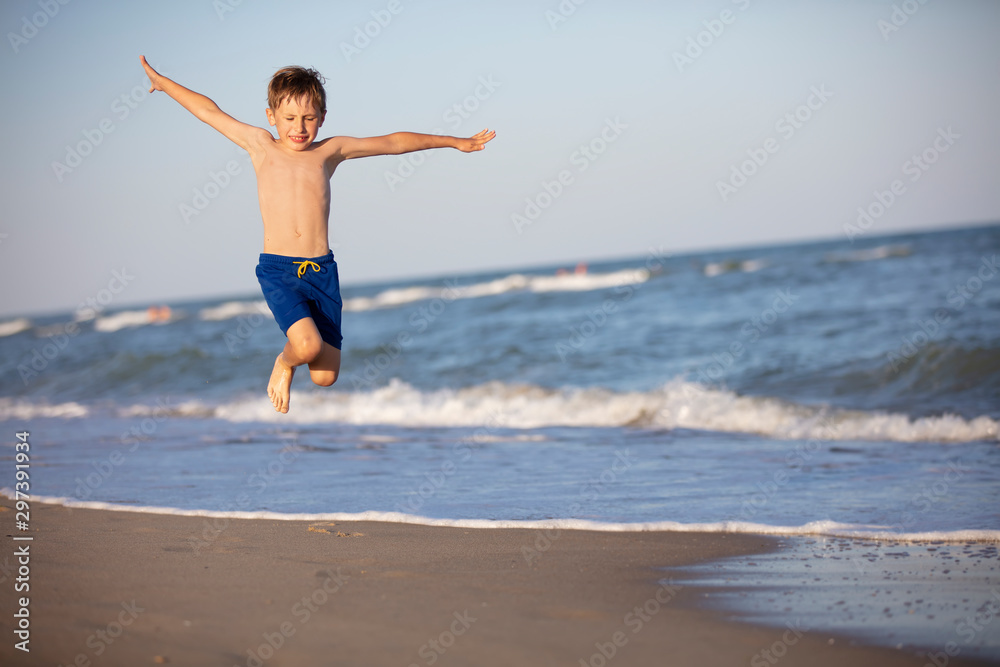 A child plays on the beach. A happy boy jumps high by the sea. Active holiday on the beach A child plays on the beach. A happy boy jumps high by the sea. Active holiday on the beach
