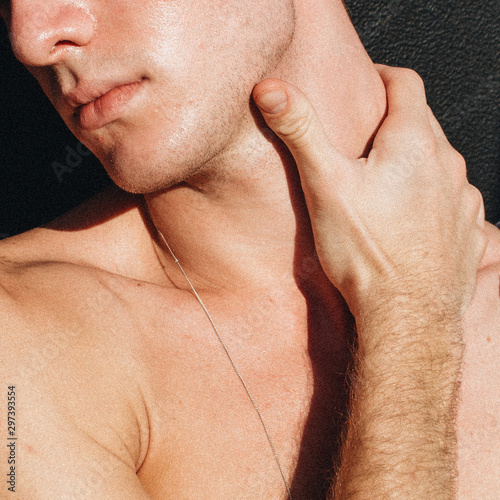 Close up view of young man holding his neck