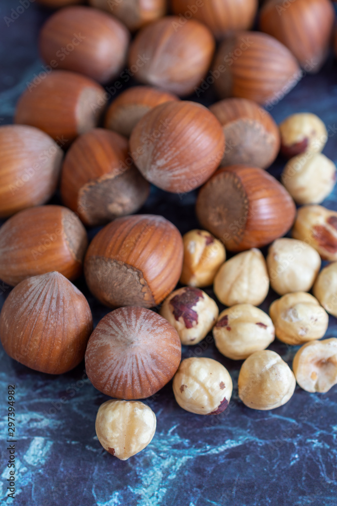 Top view of a group of hazelnuts, whole and peeled out of focus on focused blue marble background, in vertical Top view of a group of hazelnuts, whole and peeled out of focus on focused blue marble background, in vertical