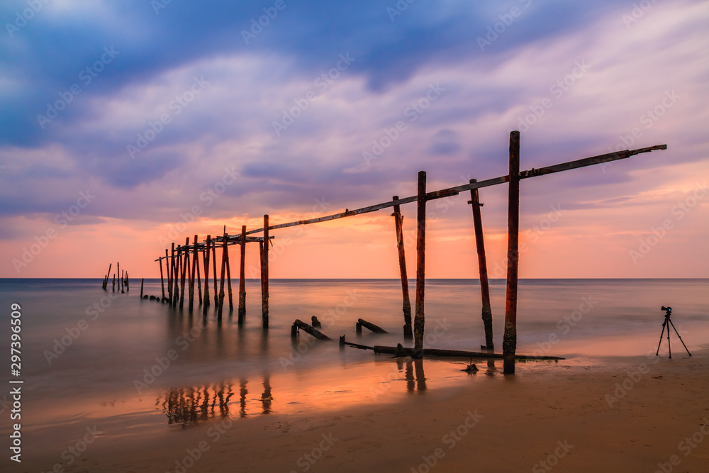 Silhouette Seascape View with Old Wooden Bridge on Tropical Beach against Dramatic Cloudy Sky at Dusk