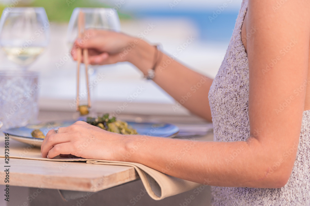 Hands of a girl whose face cannot be seen resting on a table where there are glasses of wine and a plate with food with the background out of focus. Hands of a girl whose face cannot be seen resting on a table where there are glasses of wine and a plate with food with the background out of focus.
