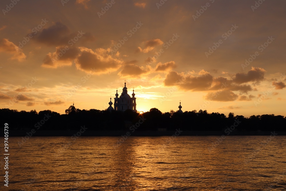 orange sunset over the river with dark church silhouetted on the