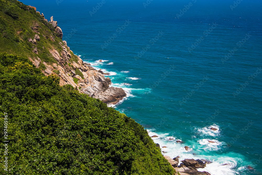 Beautiful rocks on the small Boundary island near Sanya, Hainan island, blue South China sea, China. Green trees and azure waves, top view