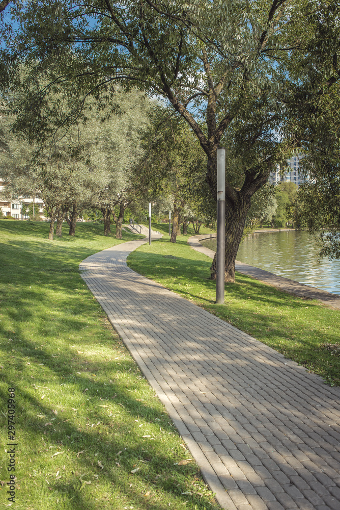 Walkway in the city park for walks along the river. Beautiful landscape of summer. Outdoor walks