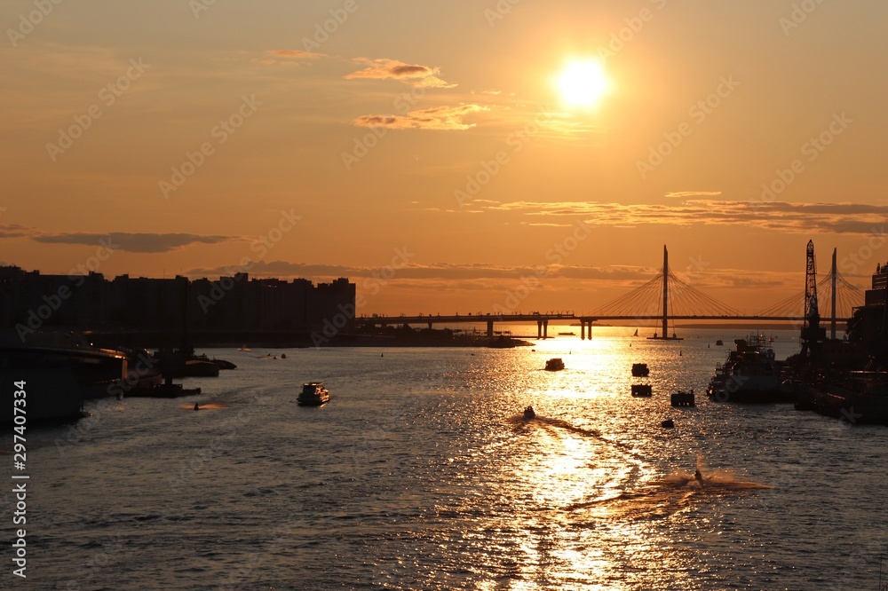 orange sunset over the river with a bridge and boats
