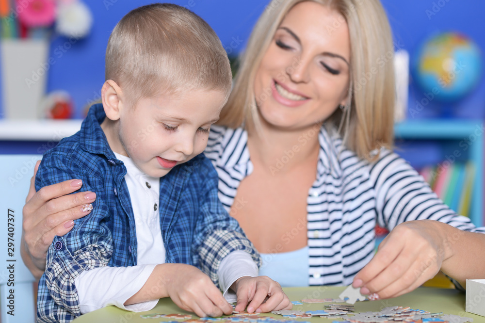 Close up portrait of mother and son collecting puzzle pieces Close up portrait of mother and son collecting puzzle pieces