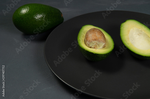 Fresh, raw avocado sliced on a black plate