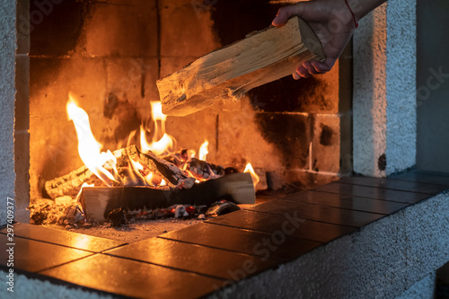 Stampa su tela Hands put firewood in a kindled fireplace on a cold winter day