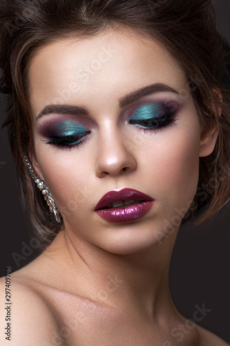 Beautiful young girl with evening colorful makeup and half closed eyes. Color lipstick with metall effect.