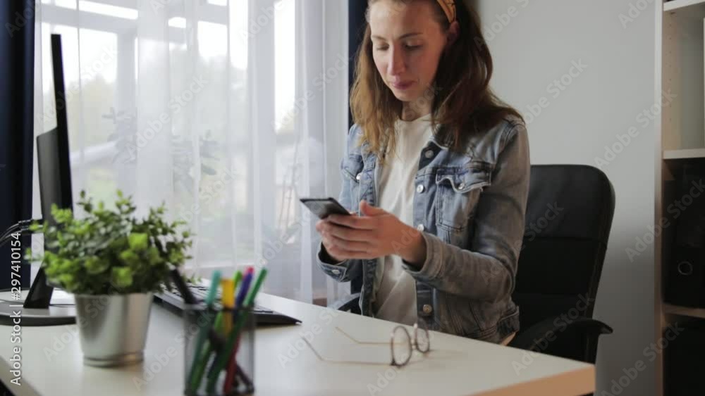 Happy smiling woman receiving nice message and typing sms on her smartphone. Woman working at her home office, freelace working Happy smiling woman receiving nice message and typing sms on her smartphone. Woman working at her home office, freelace working