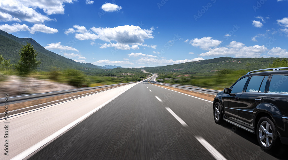 Dark car on a freeway in a beautiful area.