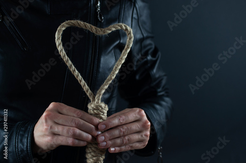 Rope in the form of a heart in the hands of a girl on a black background, the concept of relationships