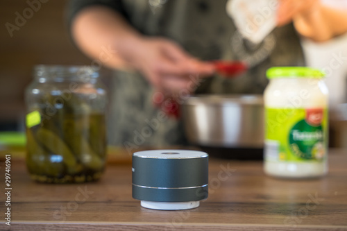 Smart ai speaker with woman cooking in the background. Smart home concept