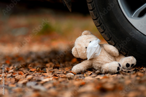 teddy bear in a medical mask crushed by a car photo