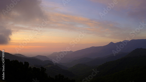 Orange sunrise on a cloudy sky and black mountain silhouette on a spectacular colourful sky © jordieasy