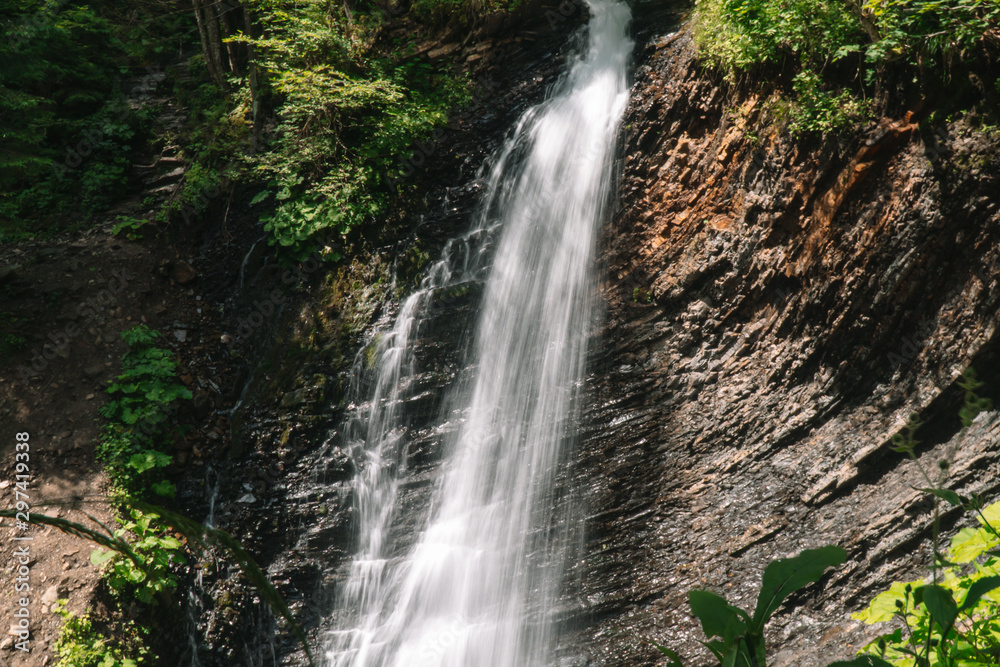 Beautiful waterfall in summer. A fast waterfall. View of the waterfall from below Beautiful waterfall in summer. A fast waterfall. View of the waterfall from below