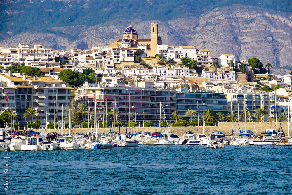 ALTEA, SPAIN - OCTOBER 14, 2019: Port of Altea with elegant yachts and view to the old town with its cathedral