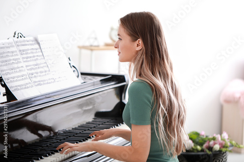 Young woman playing grand piano at home
