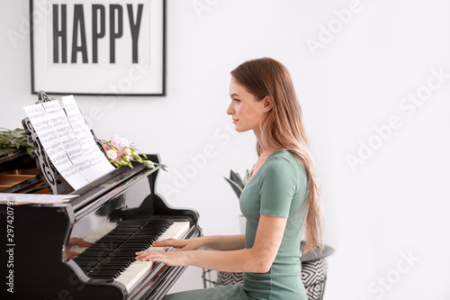 Young woman playing grand piano at home