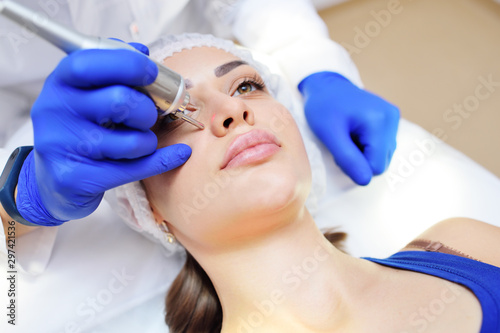 the surgeon beautician removes pigmentation and vascular nets on the skin of the patient-a beautiful young woman neodymium laser. Laser cosmetology