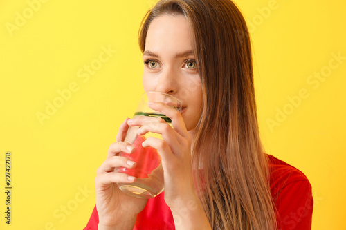 Woman drinking infused water on color background. Diet concept