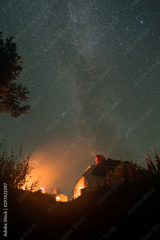 People camping with car and campfire under night sky with Milky Way People camping with car and campfire under night sky with Milky Way