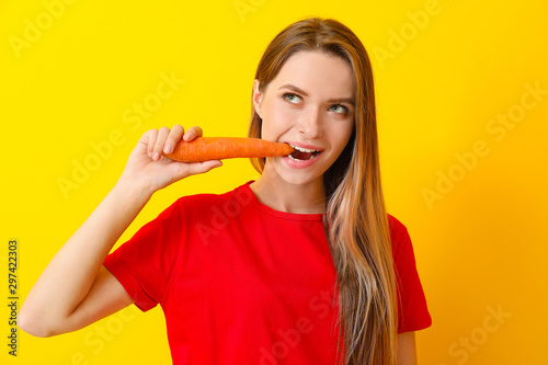 Woman eating healthy carrot on color background. Diet concept