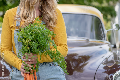 girl holding bundle of carrots at farmers market
