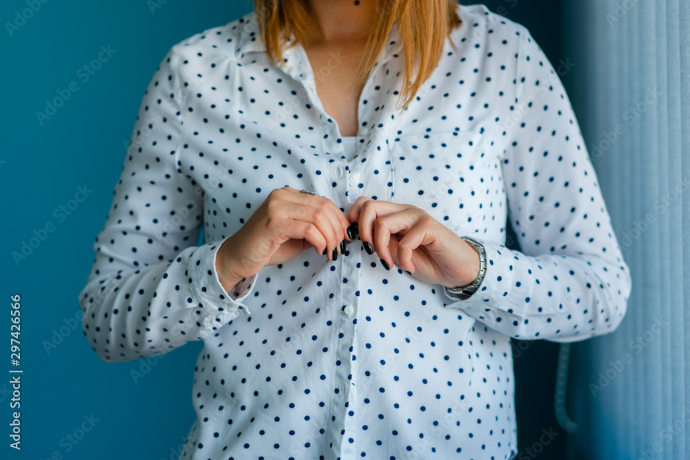 Close up on midsection of young women girl button or unbutton white shirt with spots in front of