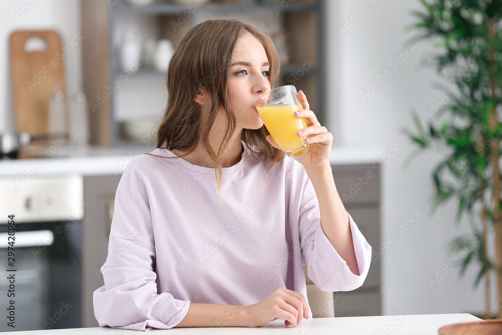 Beautiful young woman drinking orange juice in kitchen Beautiful young woman drinking orange juice in kitchen