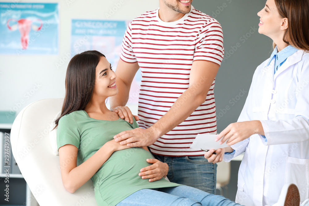 Pregnant couple visiting female gynecologist in clinic