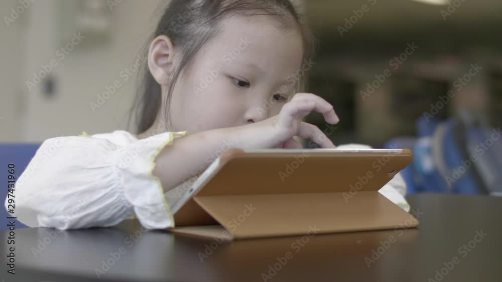 Asian little girl playing on the digital tablet with mother at library Asian little girl playing on the digital tablet with mother at library