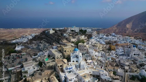 Aerial drone video of iconic small traditional village and uphill castle of Pyrgos with great views to Santorini island Cladera, Cyclades, Greece photo
