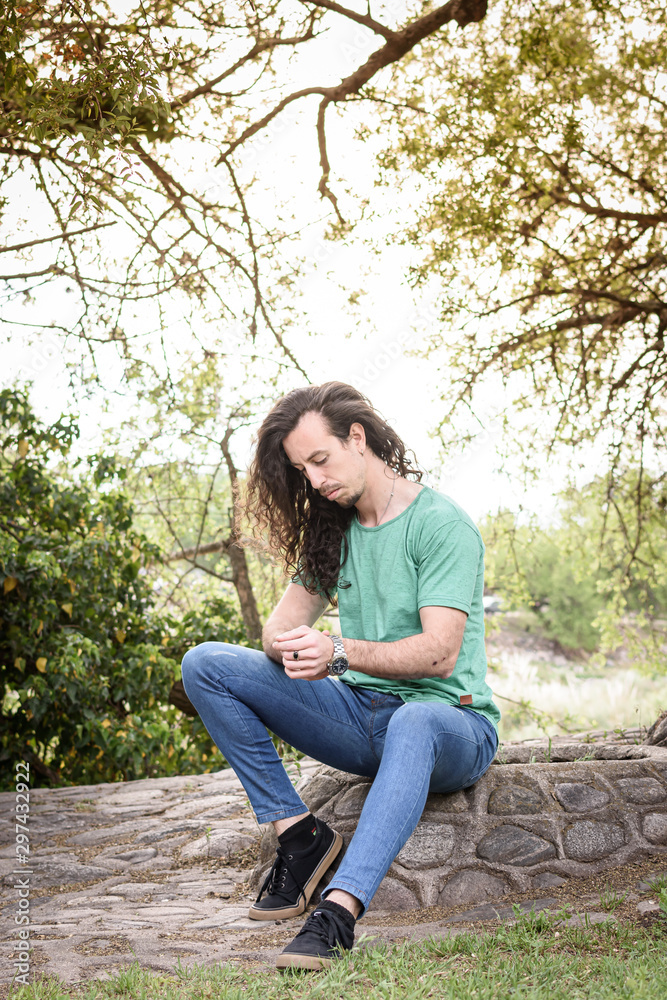 Hombre joven italiano sentado sobre piedras al aire libre Hombre joven italiano sentado sobre piedras al aire libre
