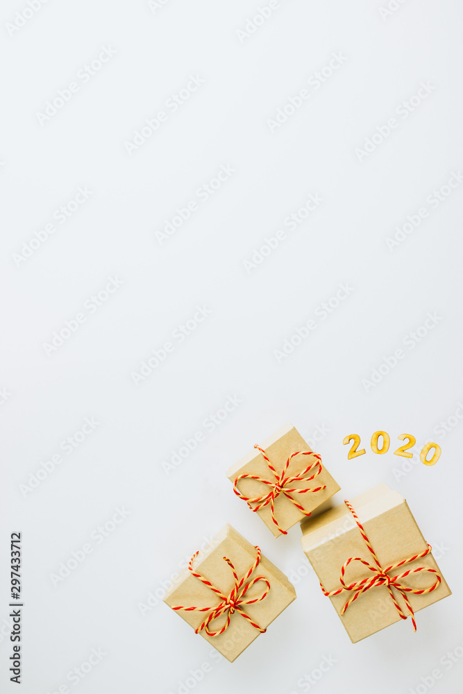 Christmas composition. Christmas gift boxes wrapped in craft paper with number 2020 on white background. Top view, flat lay, copy space. Christmas or New Year minimal concept. Christmas composition. Christmas gift boxes wrapped in craft paper with number 2020 on white background. Top view, flat lay, copy space. Christmas or New Year minimal concept.
