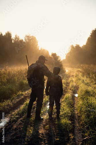 Photographie father pointing and guiding son on first deer hunt