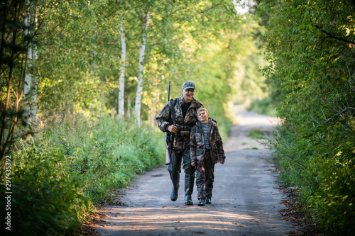 Father and son together hunting together. Walking the road in a forest.