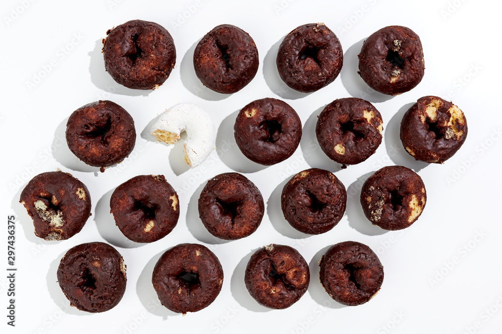 a group of chocolate donuts with one powdered sugar donut a group of chocolate donuts with one powdered sugar donut