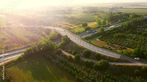 Aerial Drone Footage: Long Haul Semi Trucks Driving on the Busy Highway in the Rural Region of Italy. Beautiful Scenery of Nature and Human Logistics Progress photo