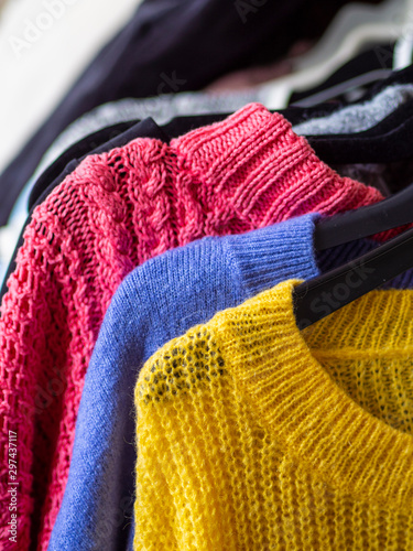 Close up rail of hanger cozy winter knitted jumpers and woolen sweaters in various colors photo