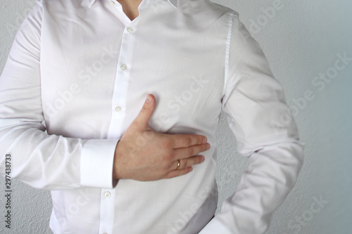 man in a white shirt holds on to the chest in the heart, symbol of problems, pain, illness, first aid, close-up