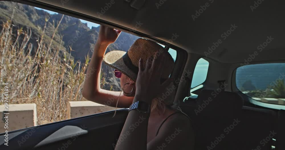 Young woman in car admiring beautiful view of mountains waving hand enjoying freedom. Portrait of girl tired of hot drive on summer day roadtrip. Young woman in car admiring beautiful view of mountains waving hand enjoying freedom. Portrait of girl tired of hot drive on summer day roadtrip.