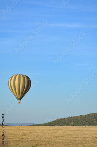A hot air balloon flies over the plains of Serengeti National Park in Tanzania, Africa; copy space