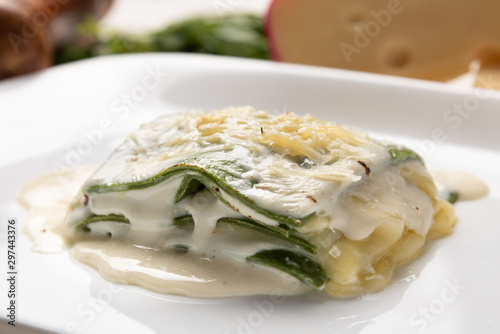 Photos Homemade fresh baked spinach sheets lasagna with bechamel and cheese sauce in a white plate