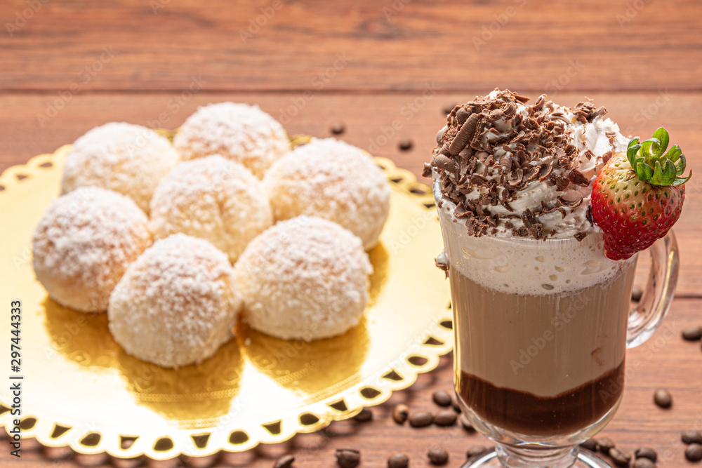 Cold coffee drink frappe (frappuccino), with whipped cream and chocolate nibs, with grains of coffee on wooden background Cold coffee drink frappe (frappuccino), with whipped cream and chocolate nibs, with grains of coffee on wooden background